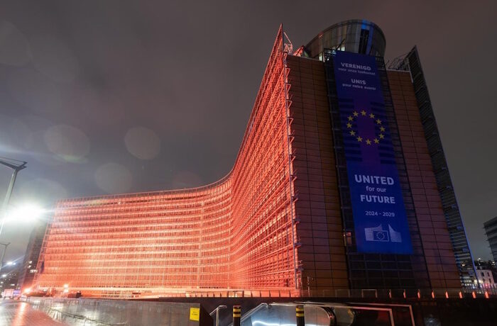 Kuva: Xavier Lejeune. Euroopan komissio tinkisi jo säädetyistä ympäristövaatimuksista hallinnollista taakkaa vähentääkseen. Komission Berlaymont-rakennus oranssiksi valaistuna marraskuussa 2025.